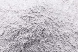 Close-up image of a pile of fine, white powder resembling silica dust. The texture appears soft and fluffy, with subtle shadows emphasizing the irregular surface.